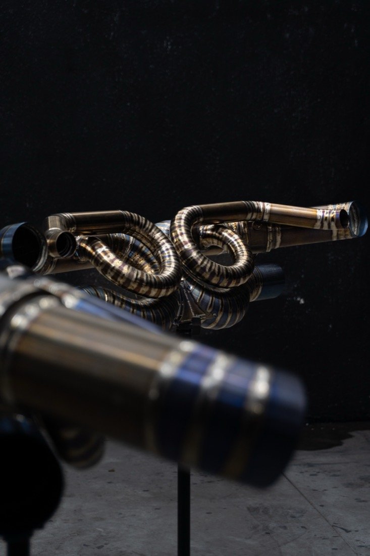 Coletor de titânio Flow Exhaust exposto em suporte, com fundo preto